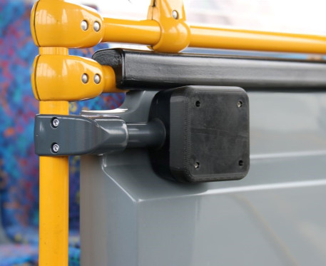 A small unbranded black box attached to the yellow poles on a bus in preparation for the installation of Motu Move equipment. 